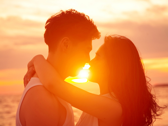 young couple kissing at sunset on beach